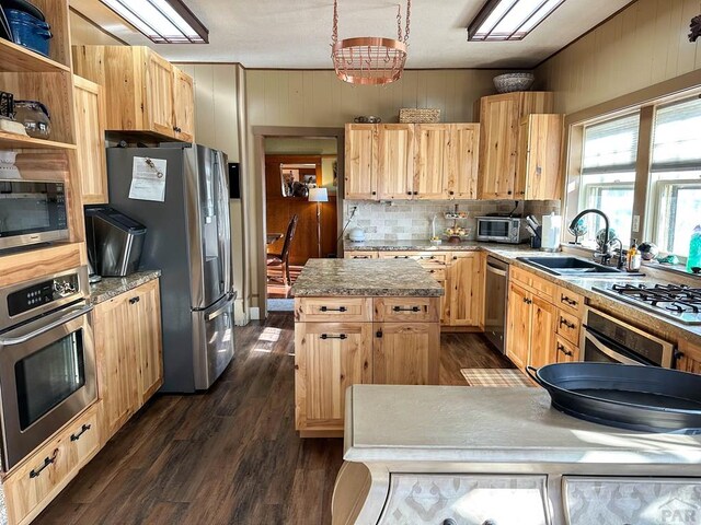 kitchen featuring a center island, open shelves, stainless steel appliances, light countertops, and a sink