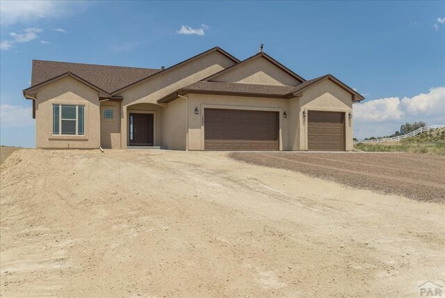 ranch-style house with a garage and stucco siding