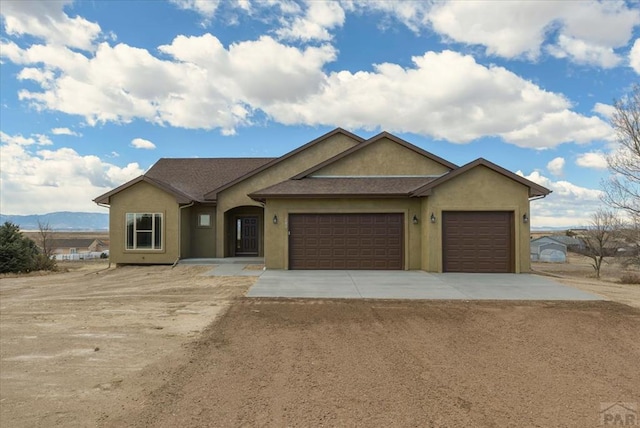 ranch-style house with an attached garage, concrete driveway, and stucco siding