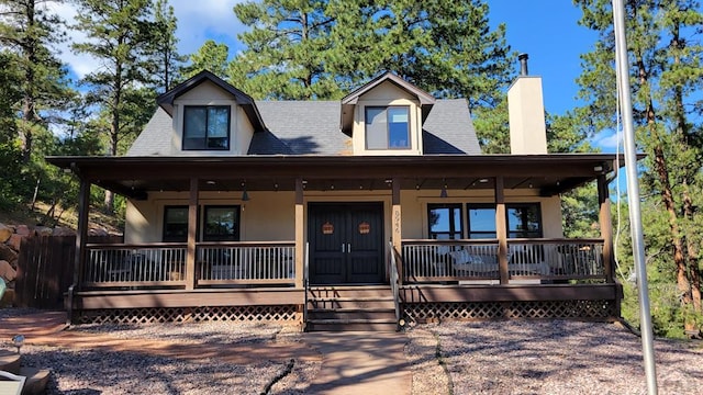 view of front of home featuring covered porch, a chimney, and stucco siding