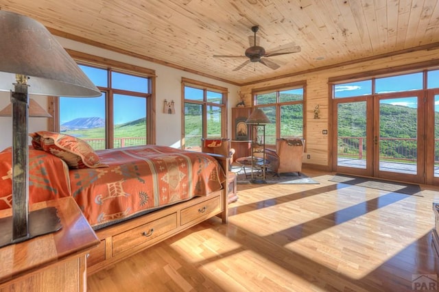 bedroom featuring wooden ceiling, a mountain view, wood finished floors, access to outside, and ornamental molding