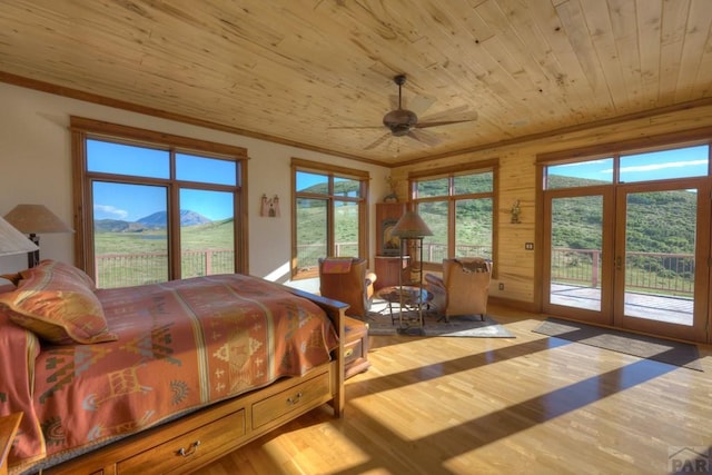 bedroom featuring access to exterior, crown molding, a mountain view, wood finished floors, and wooden ceiling