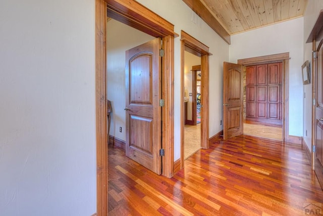 hallway featuring wood ceiling, baseboards, and wood finished floors