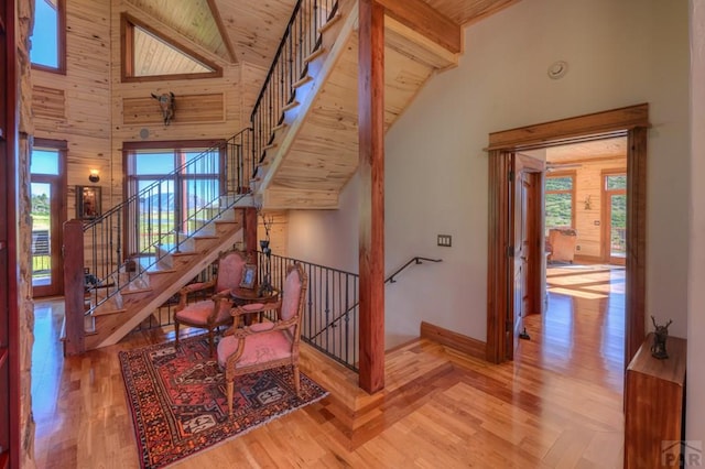 staircase with beam ceiling, high vaulted ceiling, and wood finished floors