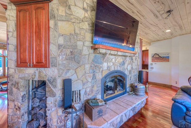 unfurnished living room featuring wooden ceiling, baseboards, a stone fireplace, and light wood finished floors