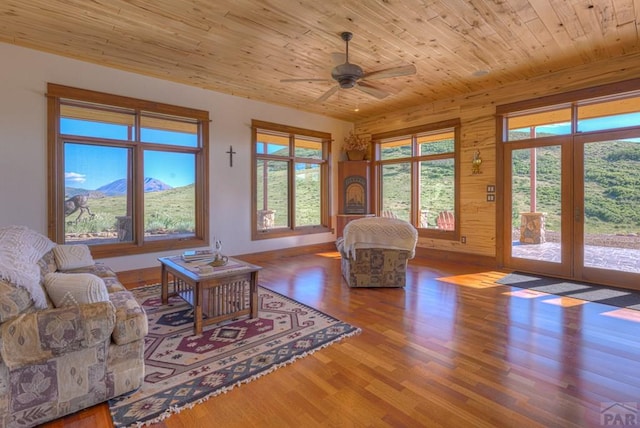 living area featuring ceiling fan, a mountain view, wood finished floors, wood ceiling, and baseboards