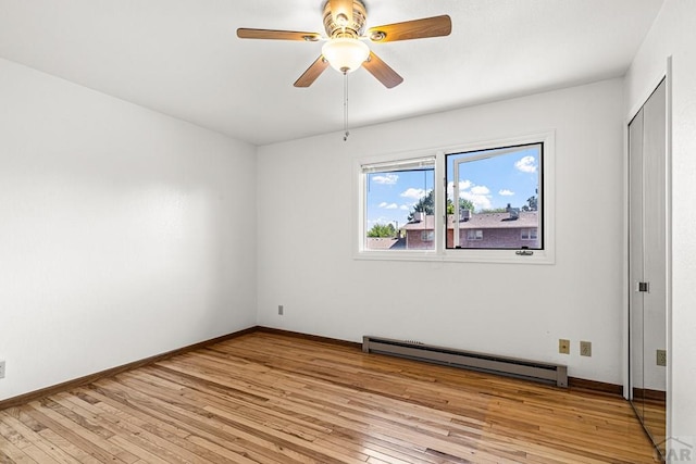 spare room featuring a baseboard radiator, light wood-style floors, a ceiling fan, and baseboards
