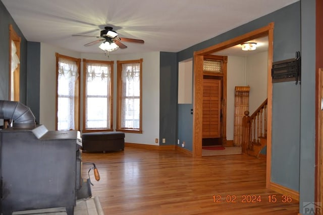 interior space with light wood-style flooring, stairs, baseboards, and ceiling fan