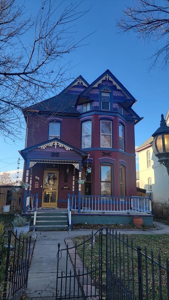 victorian house with brick siding and a fenced front yard