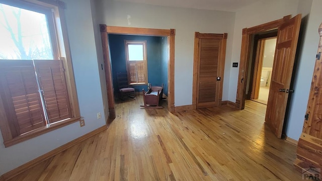 hall featuring light wood-type flooring and baseboards