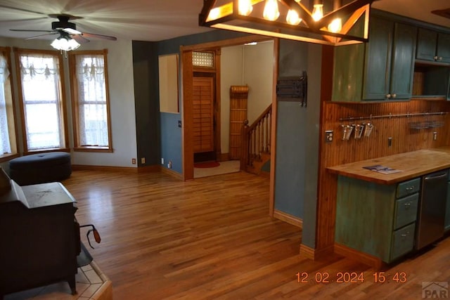 kitchen featuring wood finished floors, a ceiling fan, baseboards, wooden counters, and green cabinetry