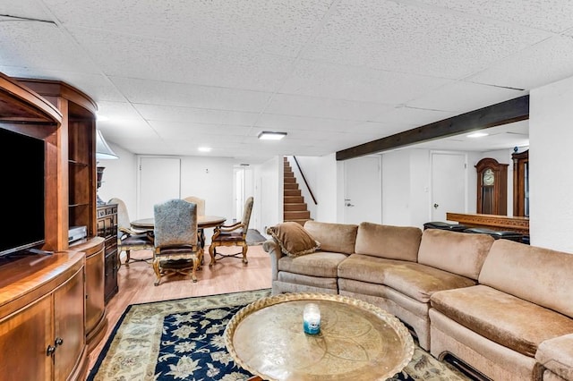 living room with stairs, a paneled ceiling, and light wood-type flooring
