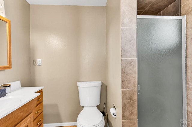 bathroom featuring toilet, vanity, and a stall shower
