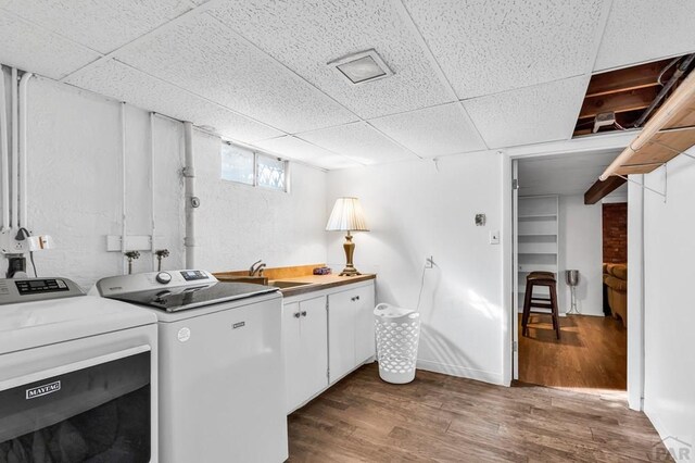 washroom with separate washer and dryer, cabinet space, dark wood finished floors, and a sink