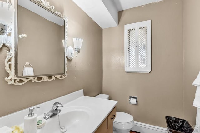 bathroom featuring toilet, baseboard heating, and vanity