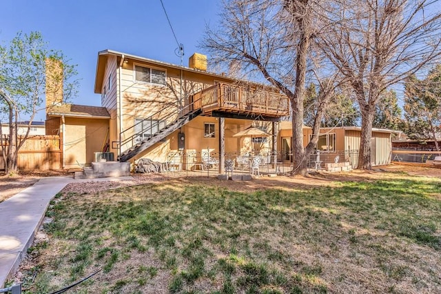 back of property featuring fence, stairway, a chimney, and a lawn