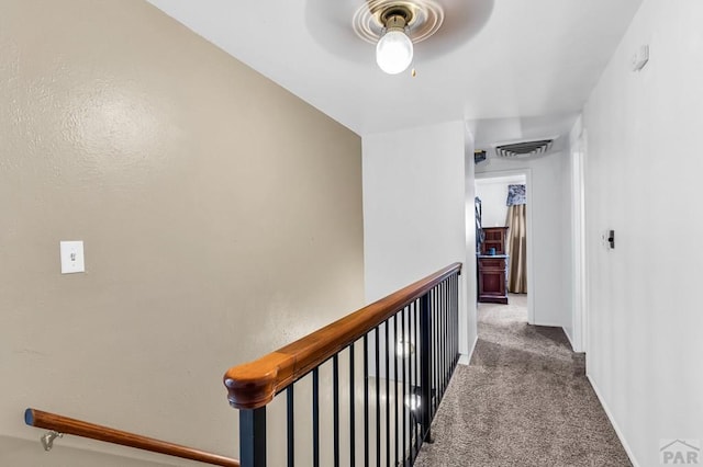 hall with an upstairs landing, visible vents, baseboards, and carpet floors