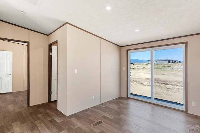 spare room featuring visible vents, ornamental molding, a textured ceiling, and wood finished floors