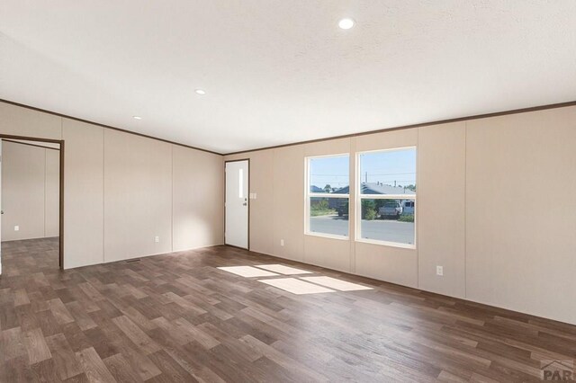 empty room featuring crown molding, wood finished floors, and a textured ceiling