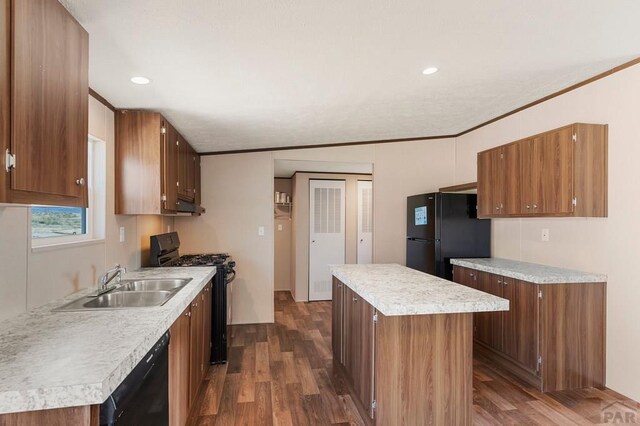 kitchen with a sink, a kitchen island, crown molding, black appliances, and dark wood-style flooring