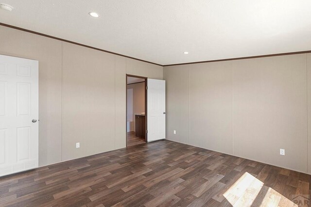 interior space with a textured ceiling, dark wood-style floors, crown molding, and a decorative wall
