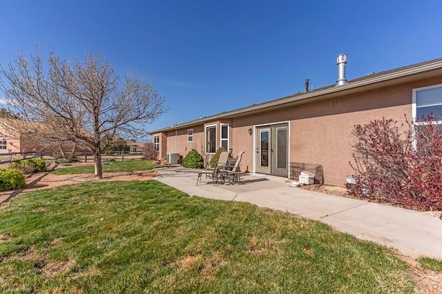 rear view of house featuring stucco siding, central AC unit, a patio, and a lawn