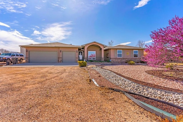 single story home featuring stone siding, driveway, a garage, and stucco siding
