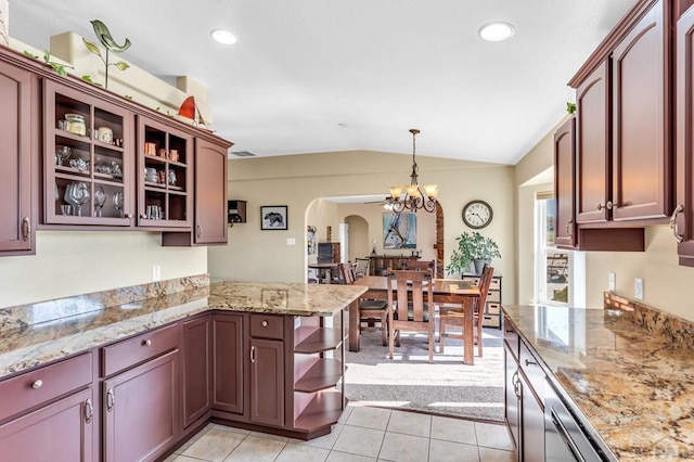 kitchen with a peninsula, arched walkways, light tile patterned flooring, vaulted ceiling, and an inviting chandelier