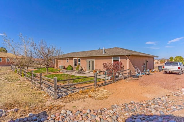 rear view of house with fence, central AC, and stucco siding