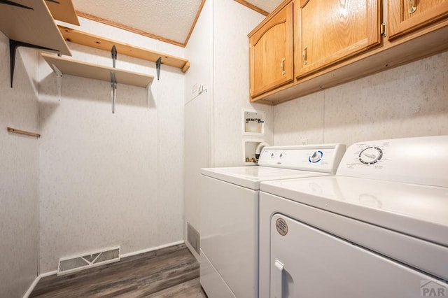 laundry room featuring dark wood finished floors, visible vents, cabinet space, a textured ceiling, and washer and dryer