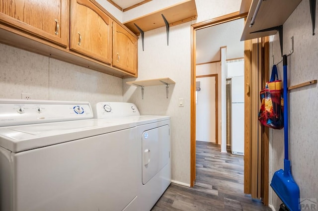 laundry area featuring cabinet space, dark wood-style flooring, and washing machine and clothes dryer