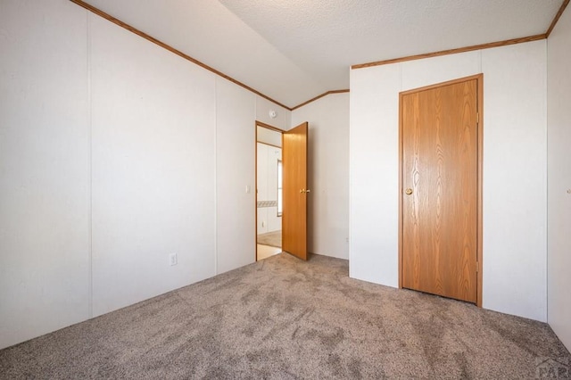 unfurnished bedroom with vaulted ceiling, carpet floors, and crown molding