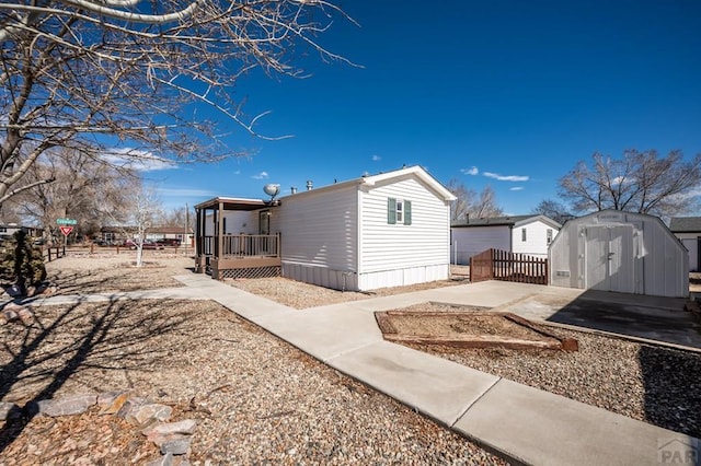 view of side of home featuring a storage shed, a deck, an outbuilding, and fence