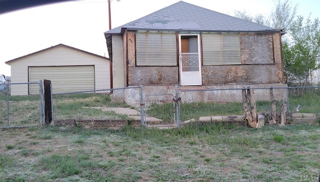 view of side of home with an outbuilding, a shingled roof, fence, and a garage