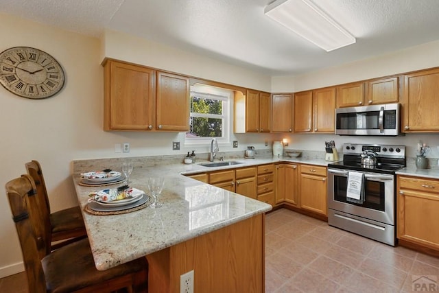 621 Twinflower Dr, Canon City, CO 81212 - kitchen featuring stainless steel appliances, a peninsula, a breakfast bar area, light stone counters, and a textured ceiling