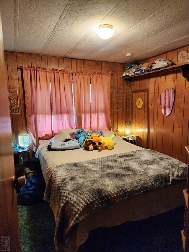 bedroom with a textured ceiling and wood walls