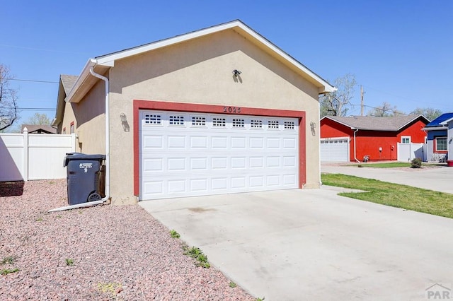 2025 Oneal Cir, Pueblo, CO 81004 - view of property exterior with stucco siding, fence, a garage, and concrete driveway
