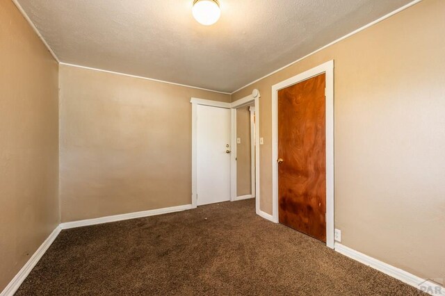 unfurnished room featuring carpet, a textured ceiling, and baseboards