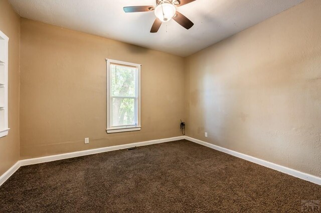 carpeted empty room with ceiling fan, visible vents, and baseboards