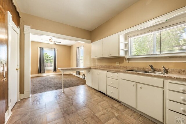 kitchen with ceiling fan, a sink, white cabinetry, light countertops, and open shelves