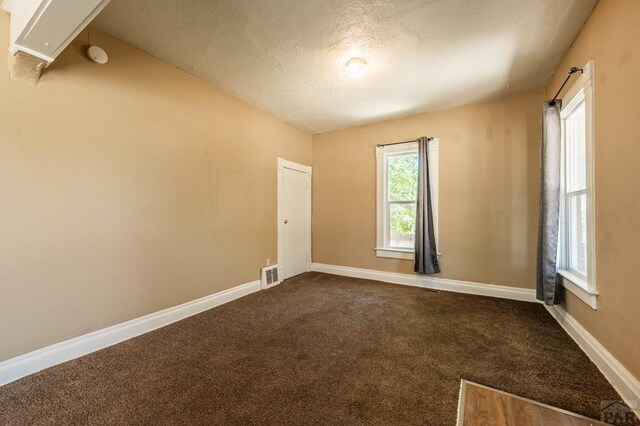 carpeted spare room featuring visible vents, a textured ceiling, and baseboards