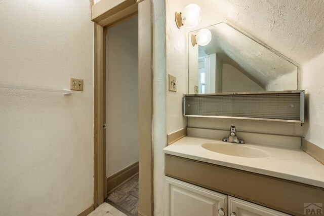 bathroom with vaulted ceiling, a textured ceiling, and vanity