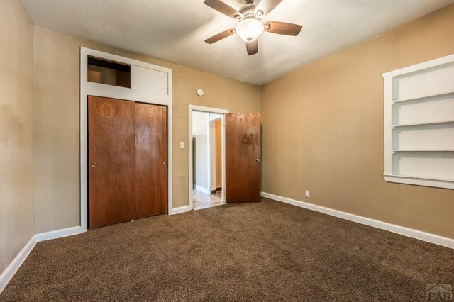 unfurnished bedroom featuring ceiling fan, a closet, dark carpet, and baseboards