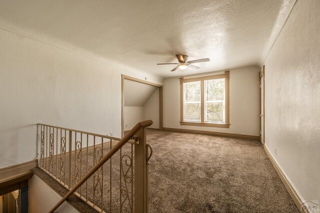 bonus room featuring lofted ceiling, a textured ceiling, carpet flooring, and a textured wall