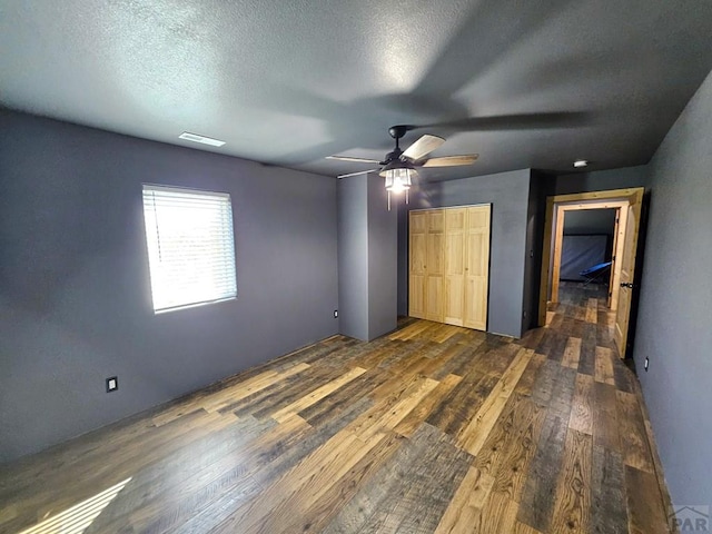 unfurnished bedroom with visible vents, ceiling fan, dark wood-style flooring, a textured ceiling, and a closet