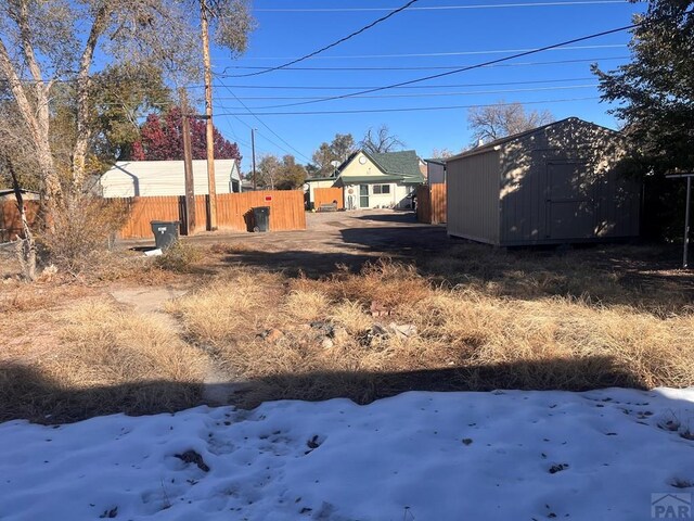 yard covered in snow with fence and a shed