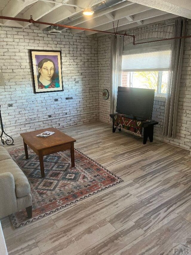 living area featuring brick wall and wood finished floors