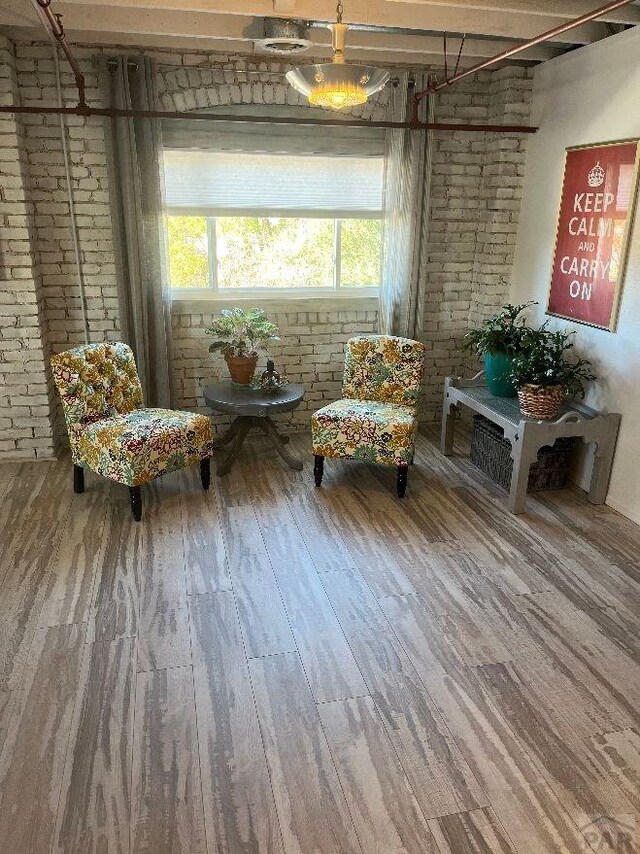 sitting room with brick wall and wood finished floors