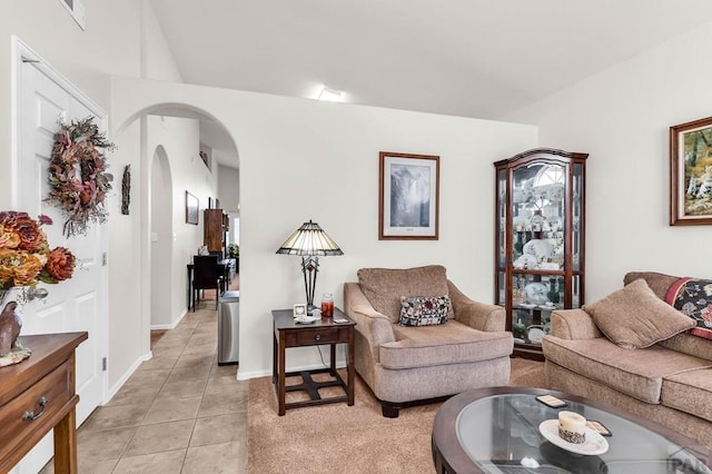 living area with visible vents, baseboards, arched walkways, light tile patterned floors, and lofted ceiling