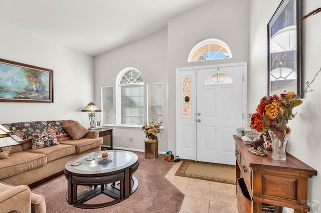 entrance foyer with light tile patterned flooring, baseboards, and high vaulted ceiling